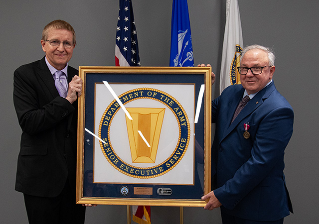 Dr. Patrick Baker, DEVCOM ARL director and Halpern hold Halpern’s framed Senior Executive Service Flag that was presented to him as a gift from his family commemorating his service as a SES member, director of the Army Research Office and his service to his nation.